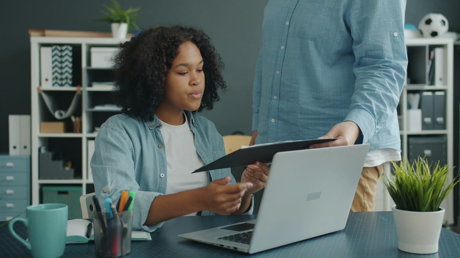 A student at her laptop taking a printed plan from her advisor
