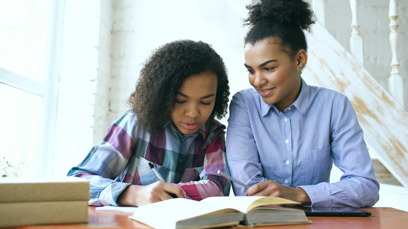 An advisor sitting beside a student, going through her notes with her